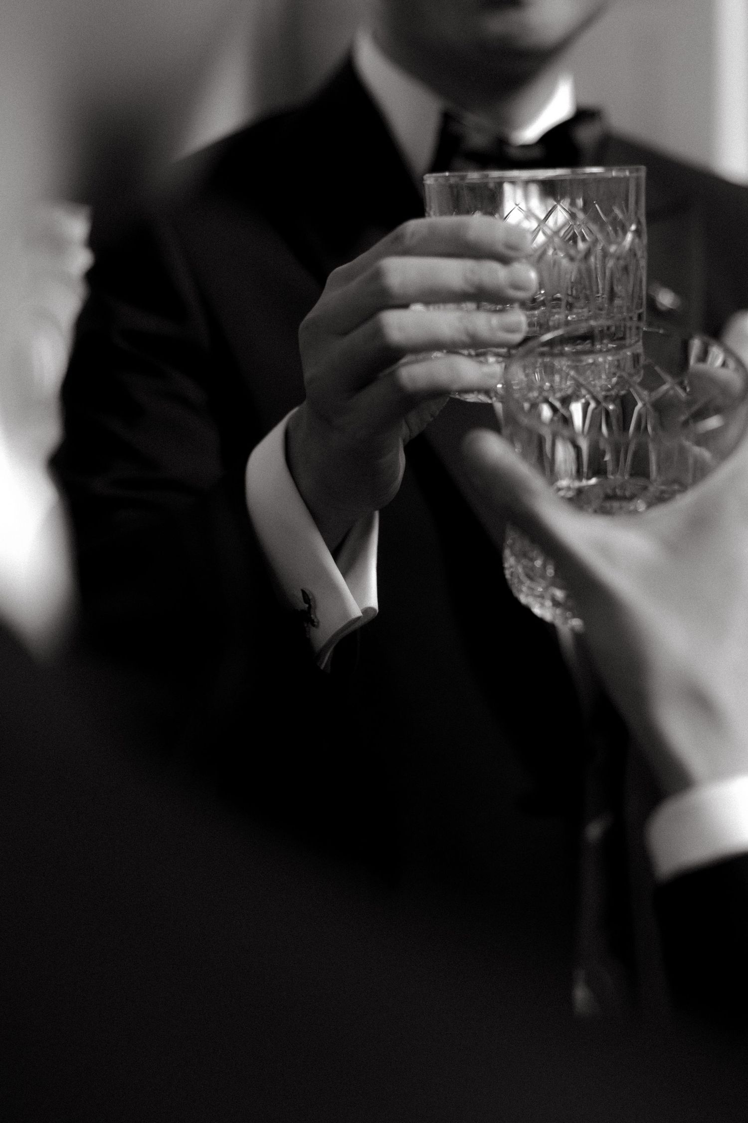 Close-up of hands holding a crystal glass at a formal event.