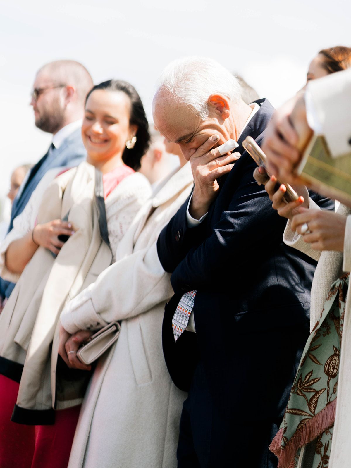 Wedding guests share laughter during an emotional outdoor celebration.
