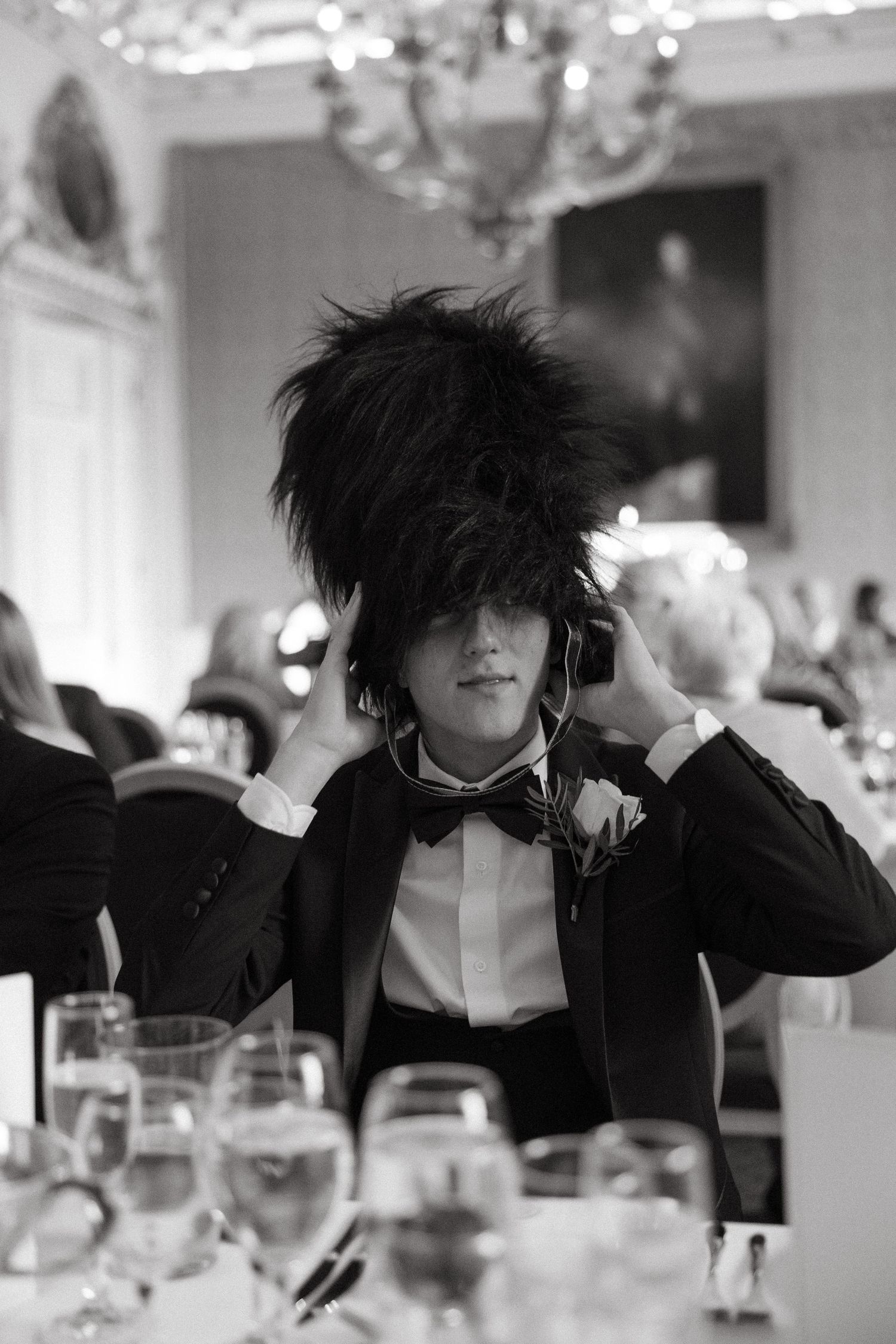 A sequence of images showing someone in a black suit with dramatic messy hair seated at a formal dinner table.