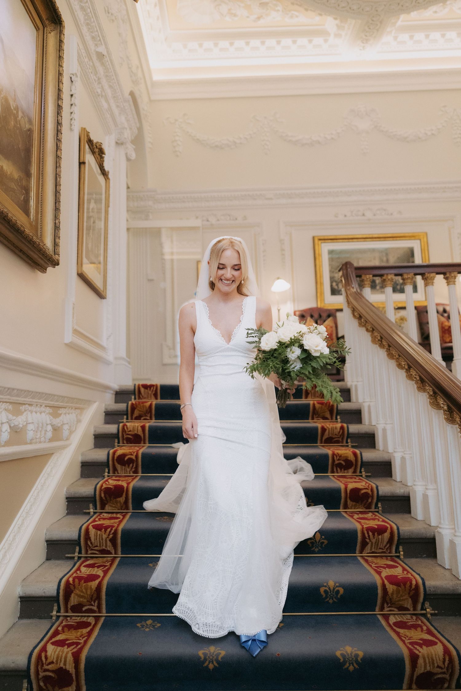 Elegant stairs with ornate white walls and dark navy runner carpet with gold accents in a classic wedding venue setting.