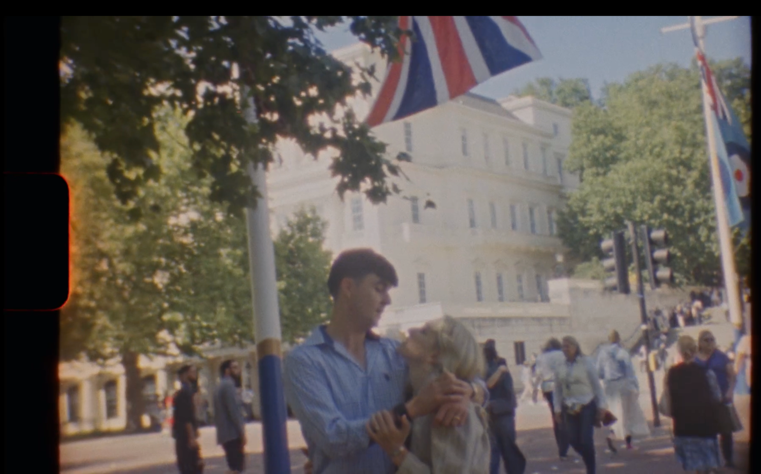 A crowd gathers on a city street with British flags and banners displayed during a public event.