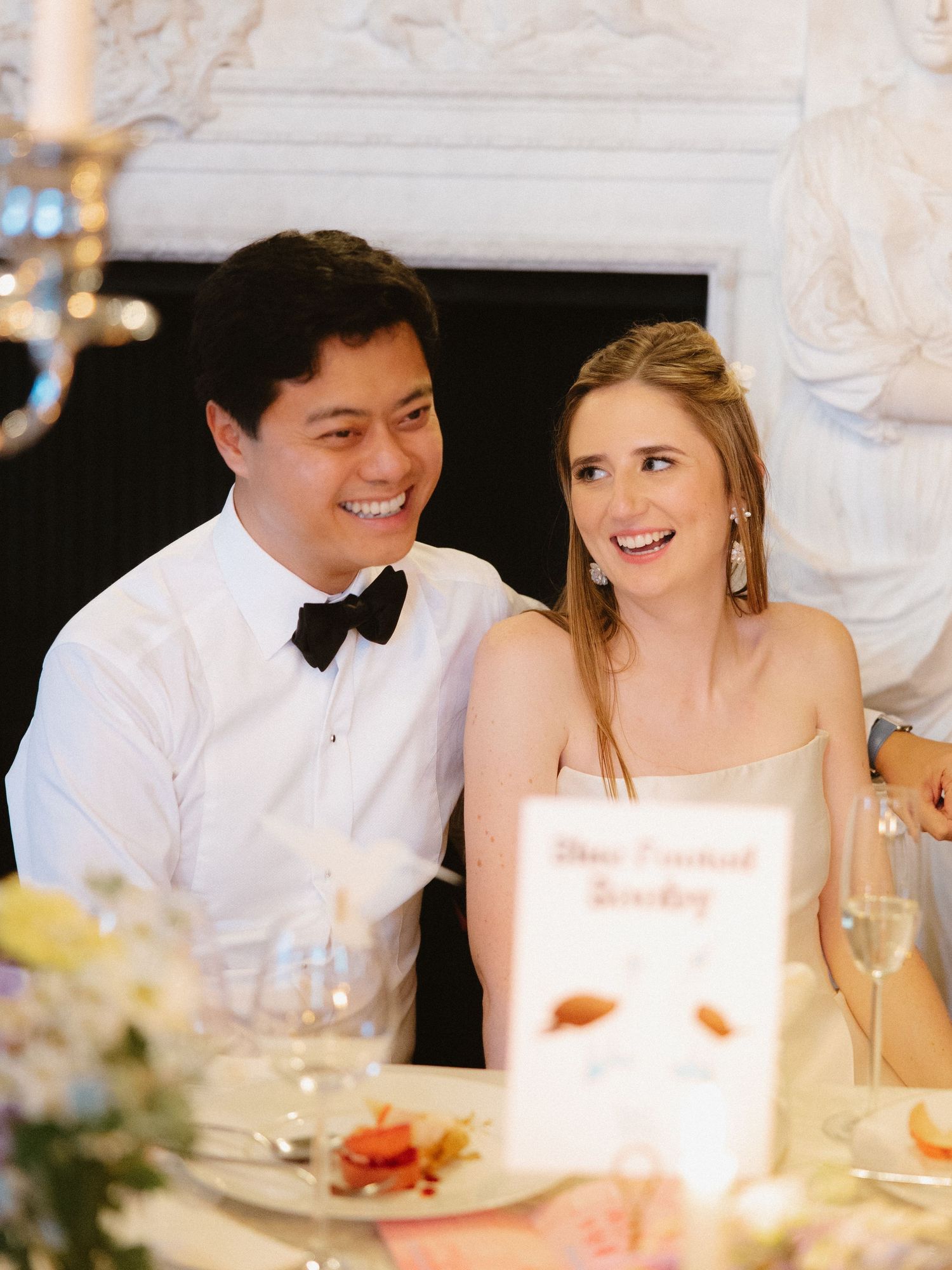 A bride and groom share a joyful moment during their wedding reception in an elegant dining room.