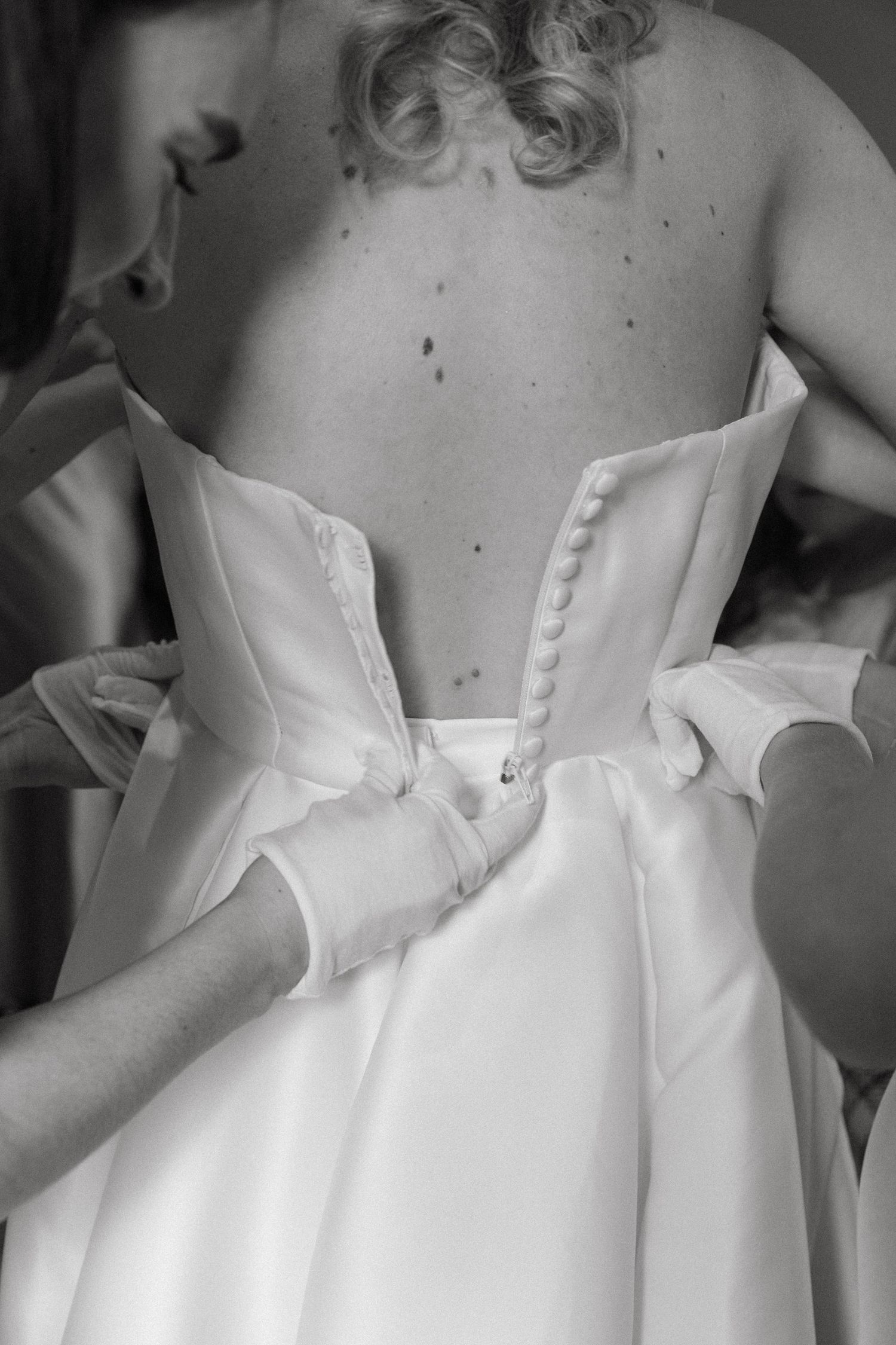 Close-up detail of white wedding dress buttons and bow on the back.