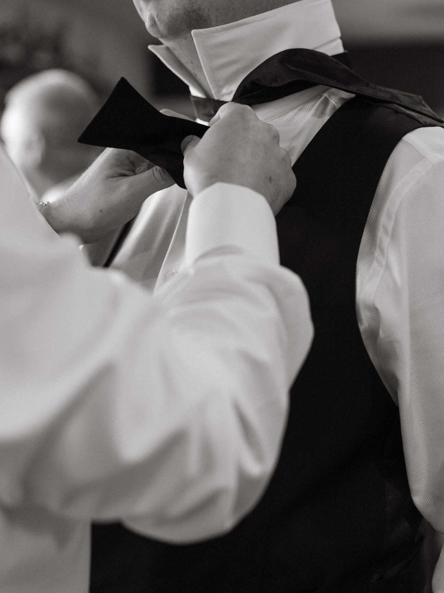 Close-up detail of formal white dress shirt and black tuxedo at a wedding.