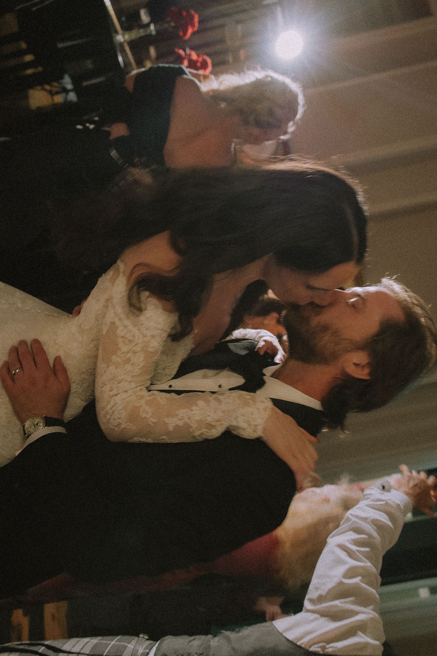 A couple in wedding attire share a romantic kiss on the dance floor during their first dance at their reception.