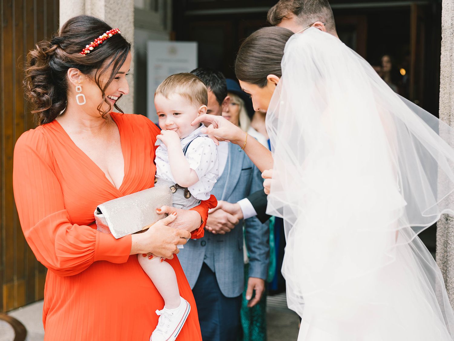 A tender moment at a wedding as attendees gather around a small baby dressed in light blue.