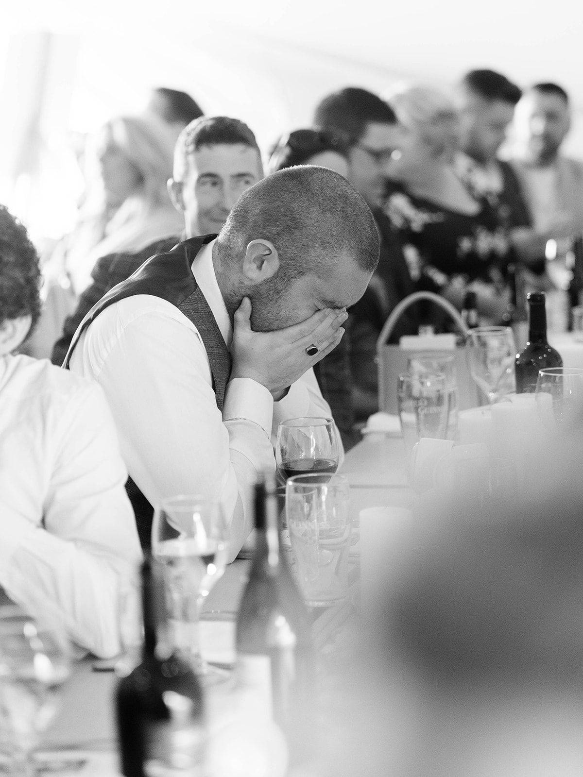 Black and white photo of emotional wedding reception guests seated at dinner tables.
