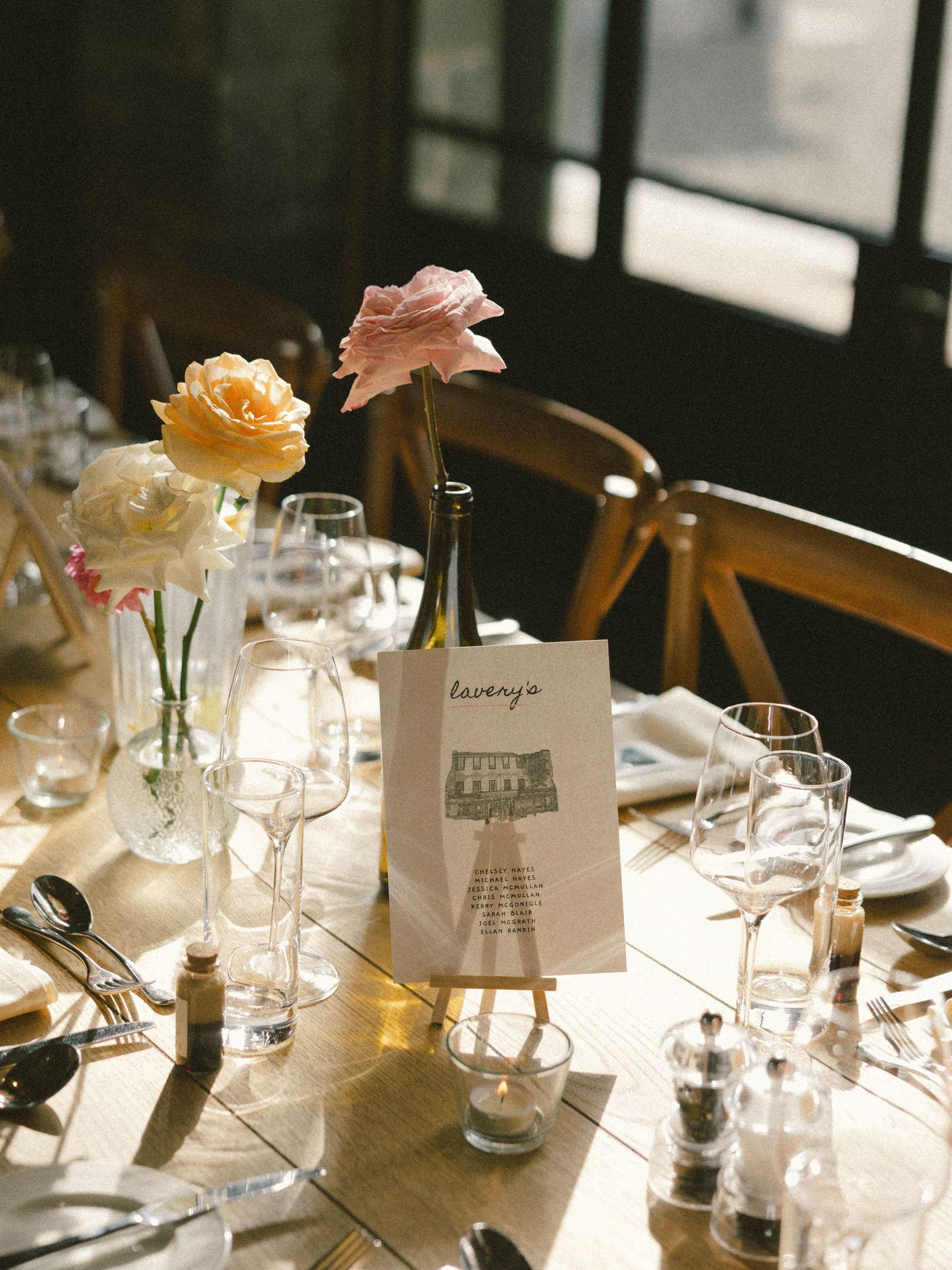 Elegant wedding reception table settings with delicate floral centerpieces and place cards in soft lighting.