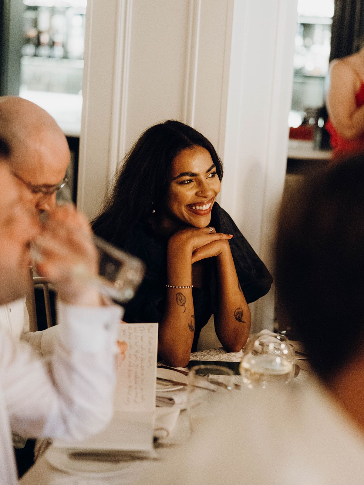 Guests enjoying conversation and laughter during an elegant dinner party at a restaurant.