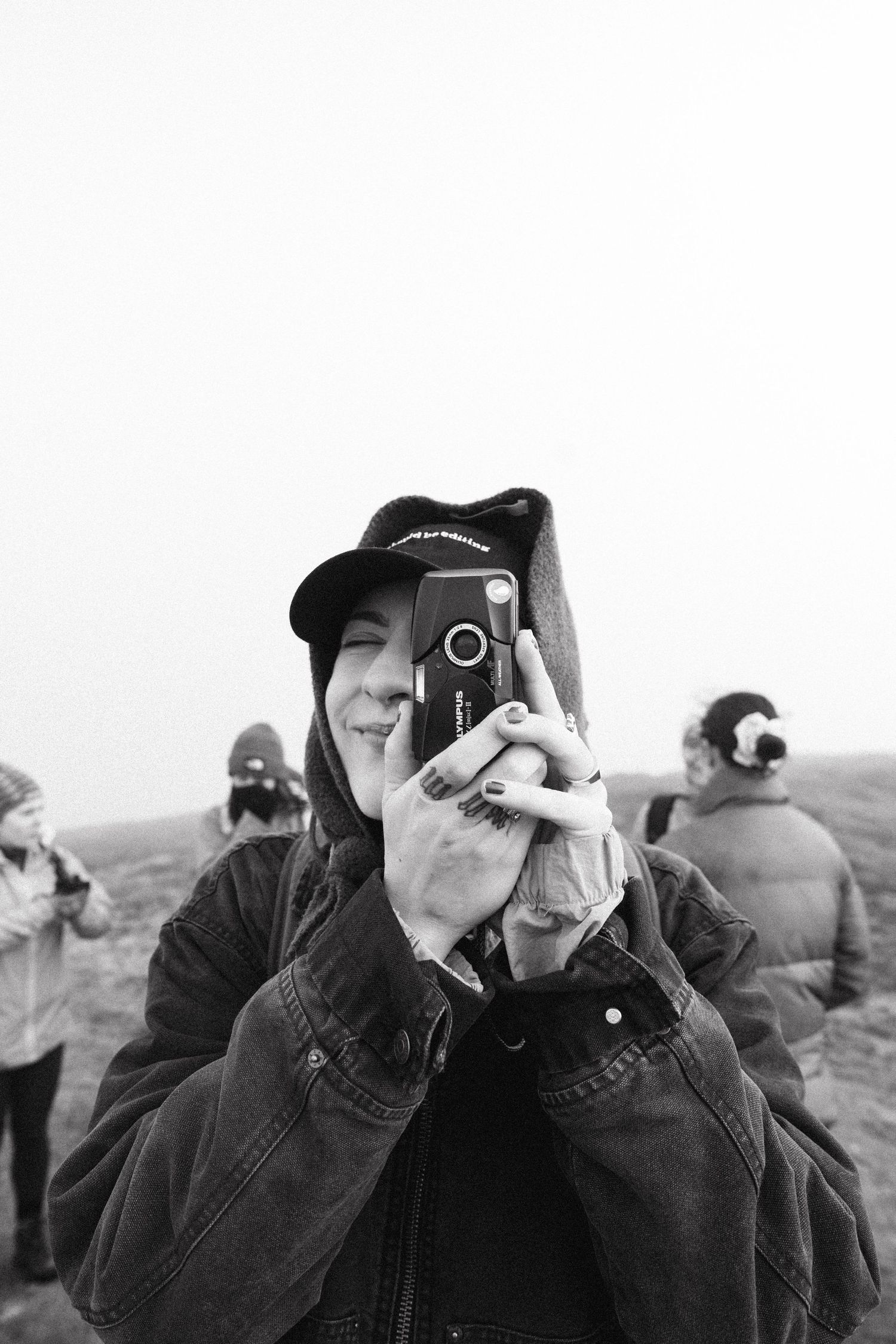 Black and white photo series of photographers using cameras to take pictures outdoors.