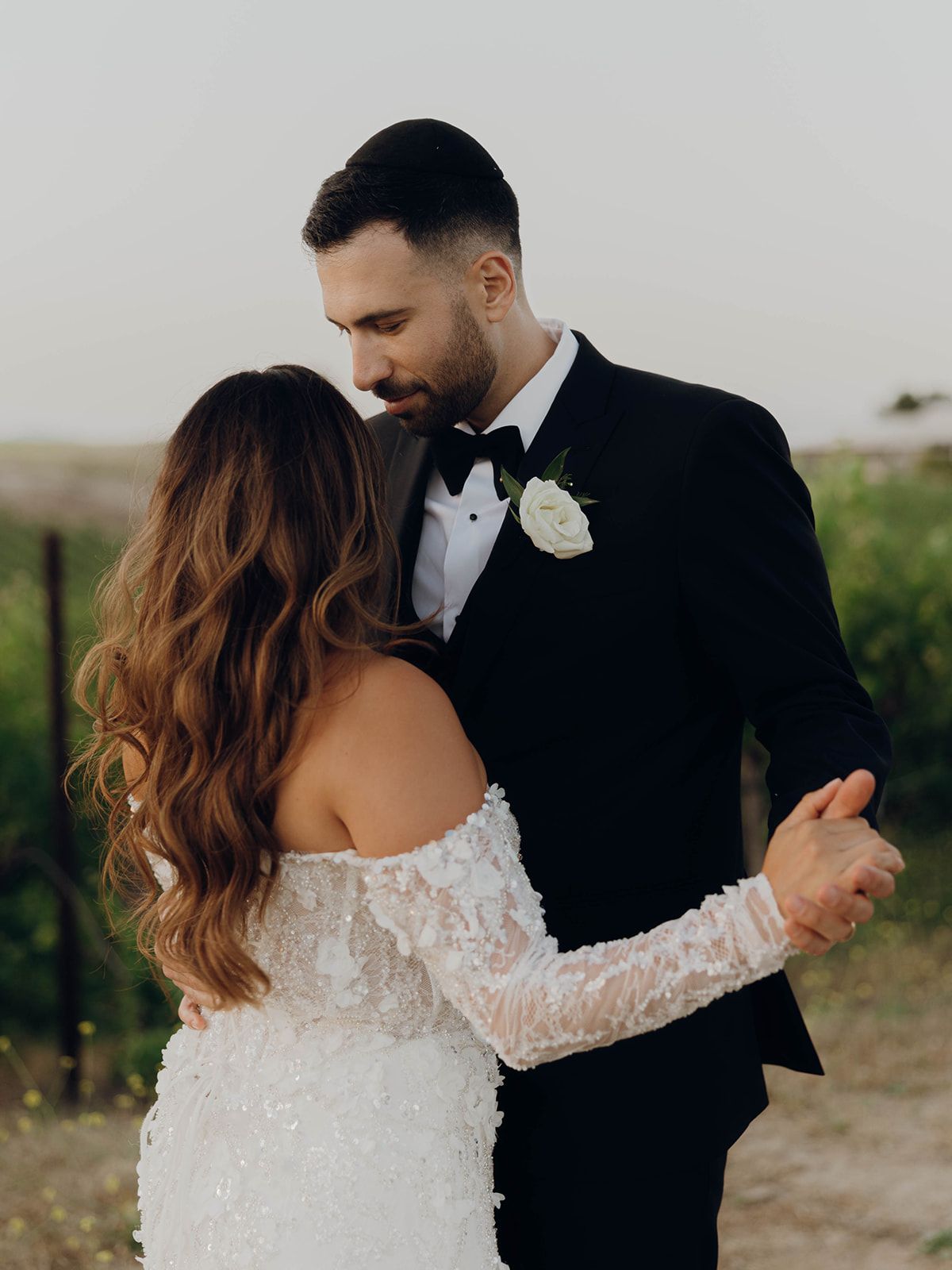 Newlywed couple sharing an intimate moment together in formal wedding attire with a white rose boutonniere.