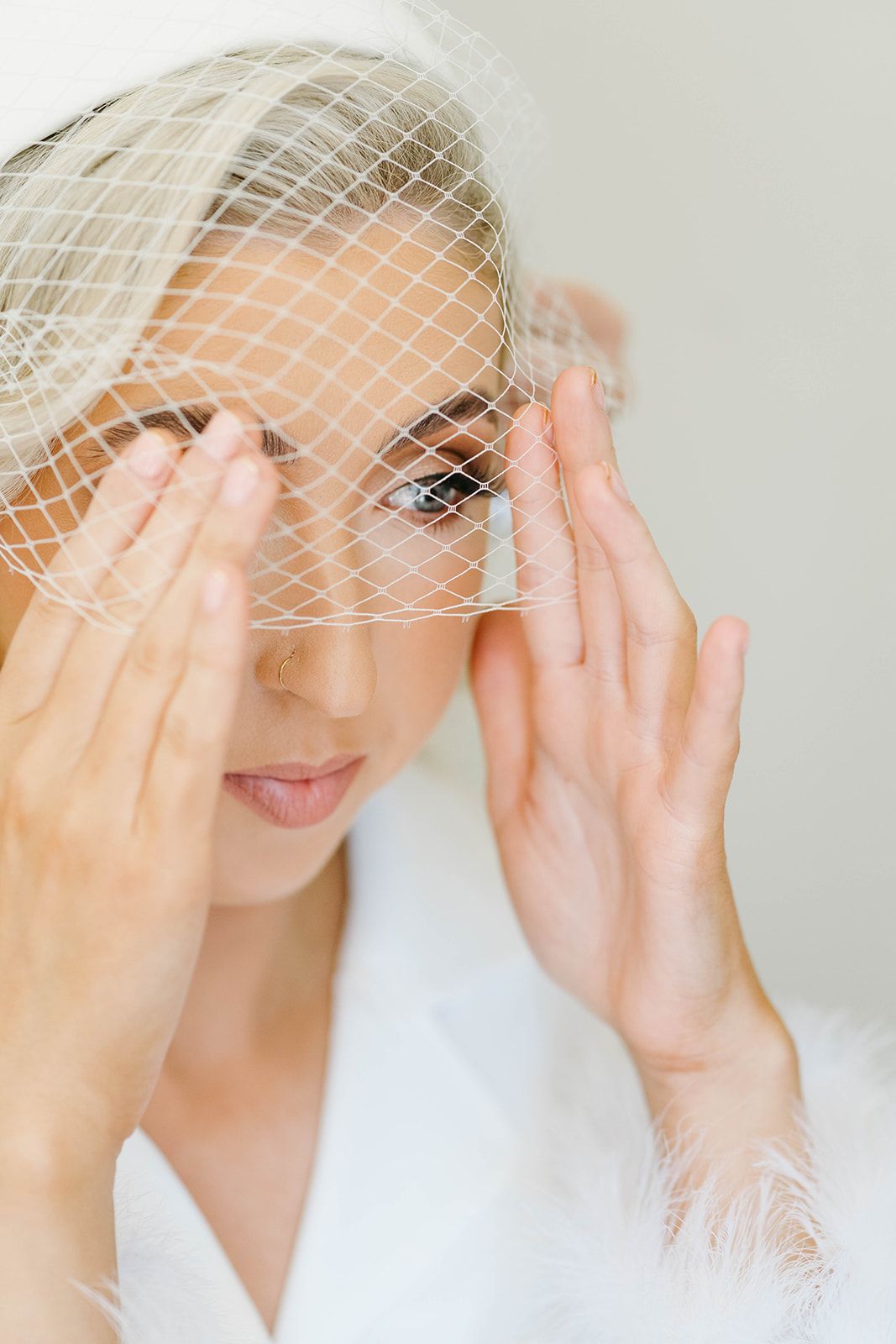 A bride in white lace wearing a birdcage veil poses playfully in a series of romantic portraits.
