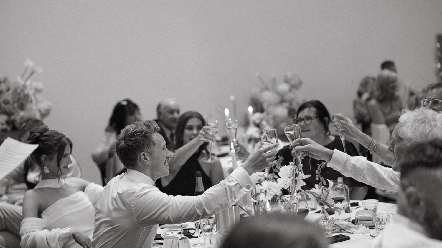 A black and white panoramic photo shows people seated at long tables during a formal dinner gathering.