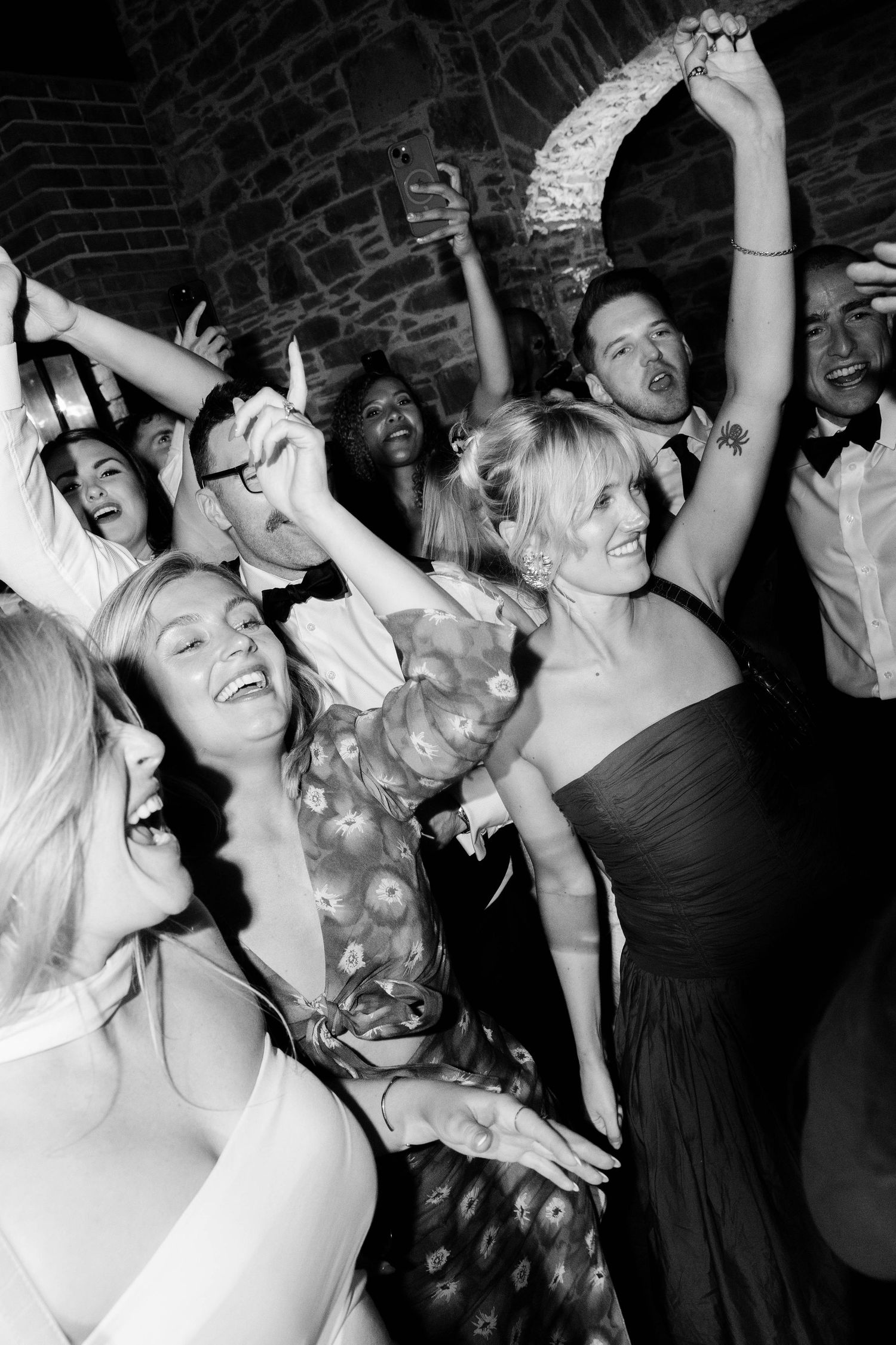 Wedding reception party guests dancing and celebrating with hands raised in joyful excitement.