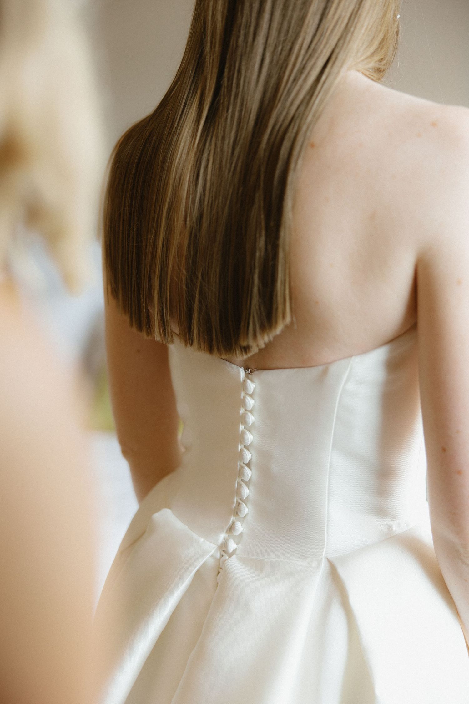 Close-up view of a white wedding dress back detail showing delicate lace-up corset style closure.