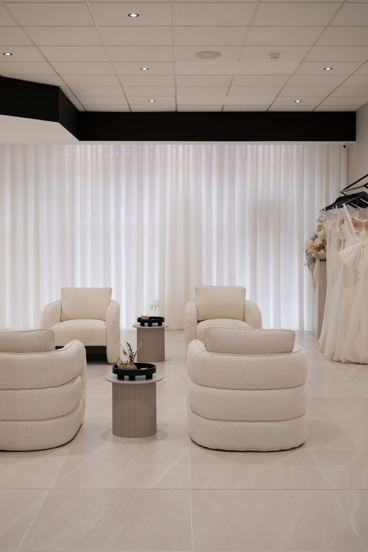 Modern bridal boutique interior with white circular seating pods and minimalist decor on white tile flooring.