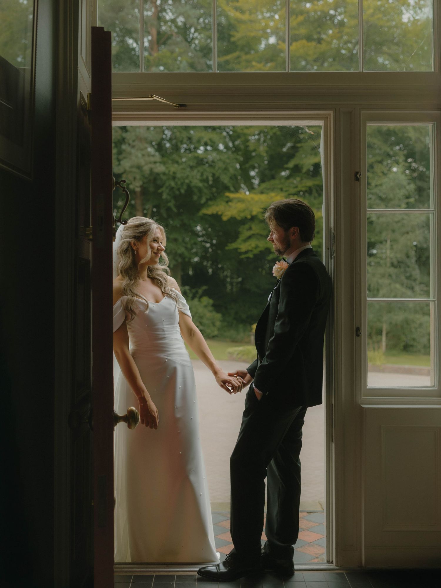 A romantic wedding moment silhouetted in a doorway with natural light streaming through windows.