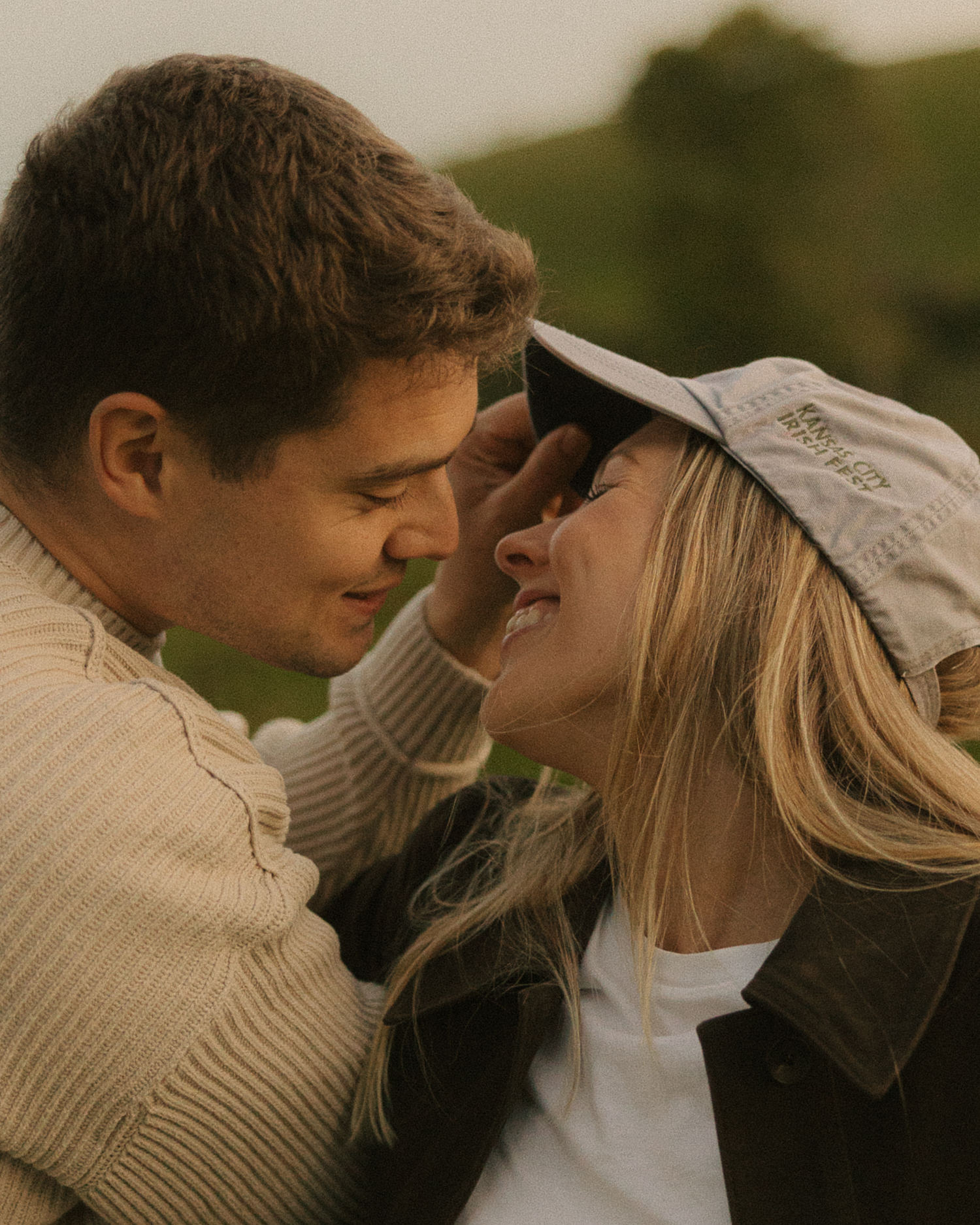 A romantic couple sharing an intimate moment while wearing casual sweaters outdoors.