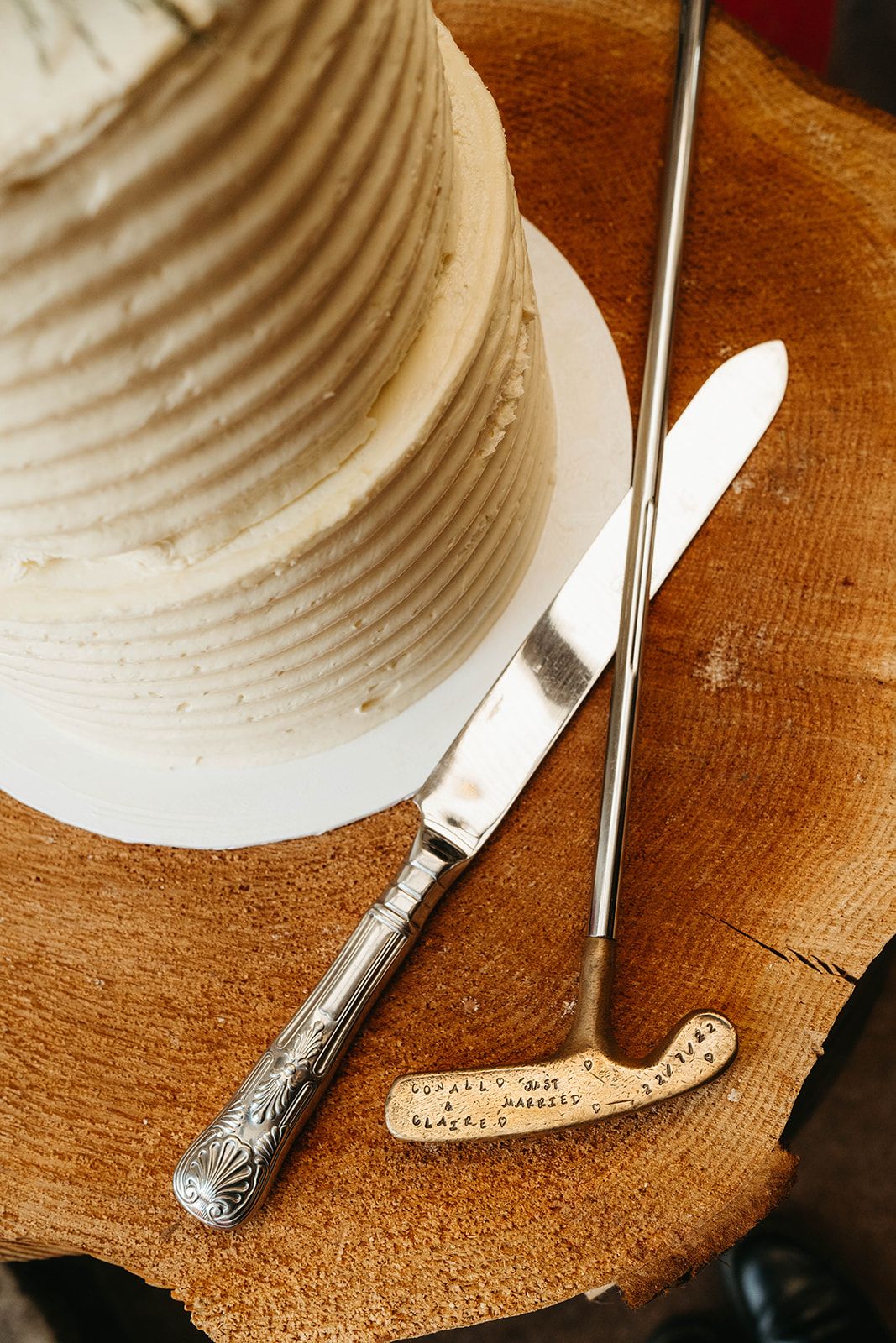 Wedding cake decorating tools including knife and texturing tool on wooden surface with white fondant.