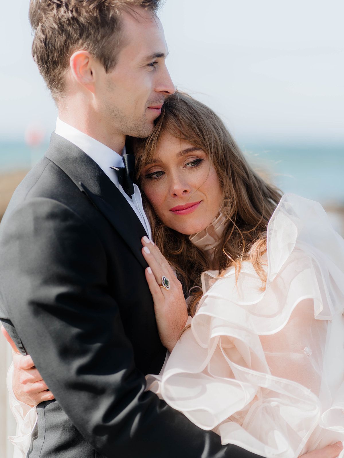 Intimate seaside portrait of newlyweds in classic wedding attire.