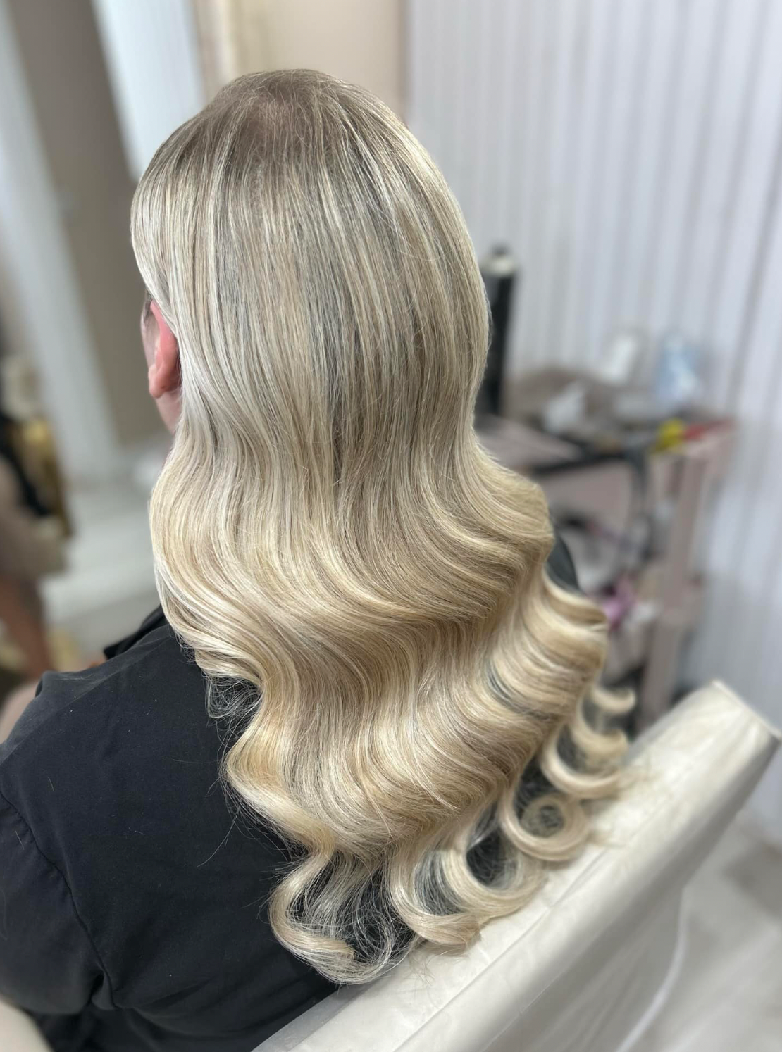 Beautiful blonde wavy hair styled in glamorous Hollywood waves with a perfect ash blonde balayage color.