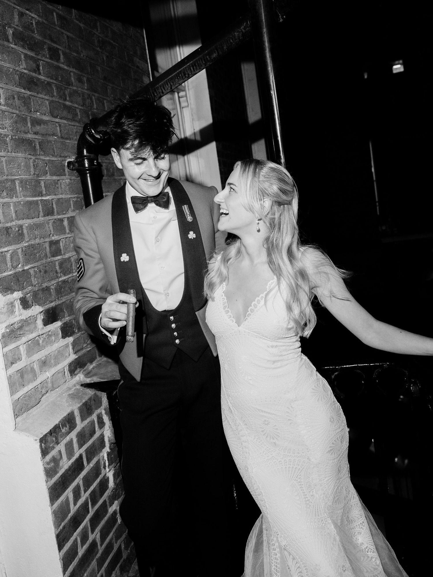 Black and white sequence of three candid party photos showing a couple dancing and laughing together against a brick wall.