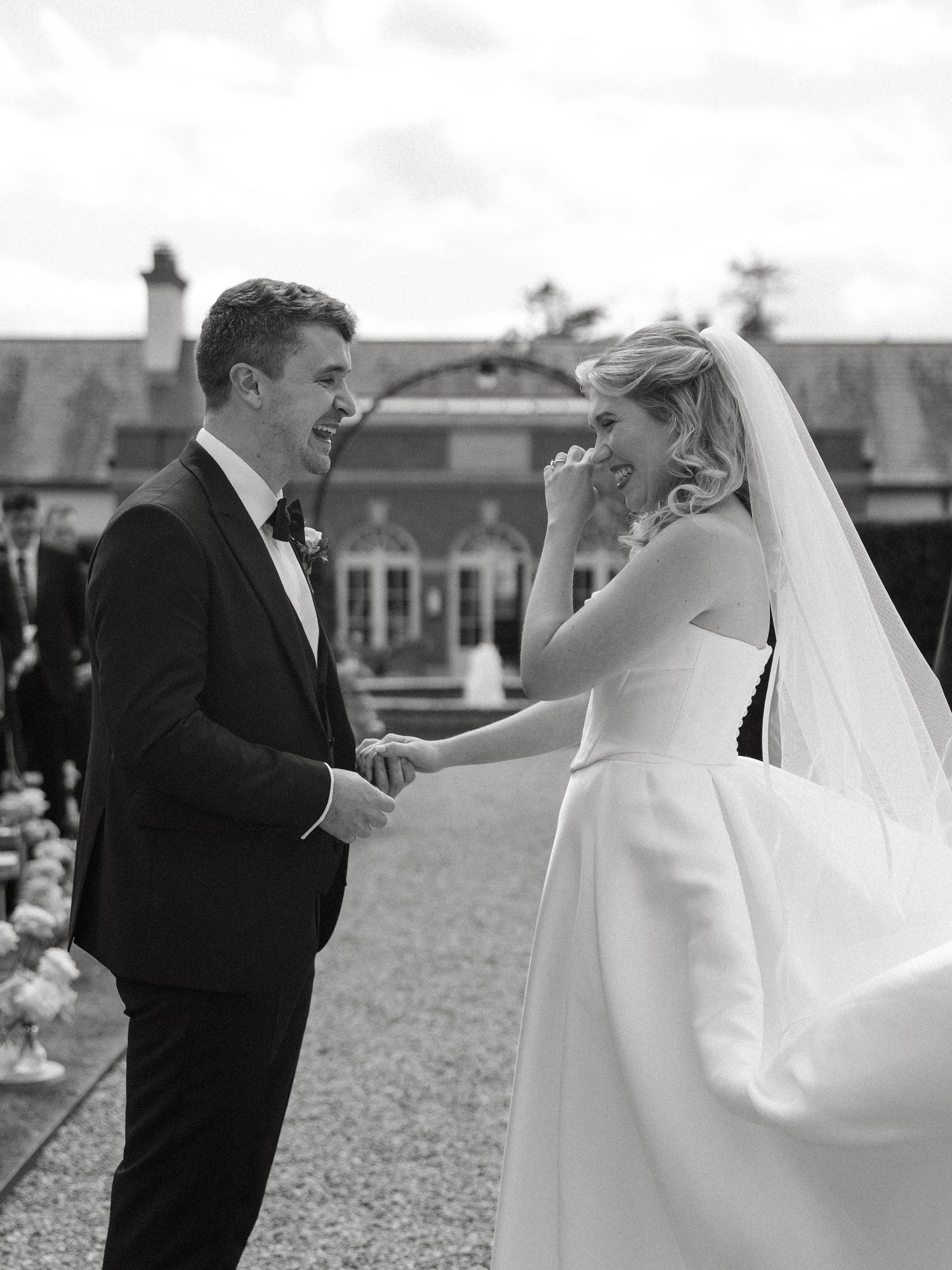 A couple playfully interacting with a wedding veil in an outdoor setting.