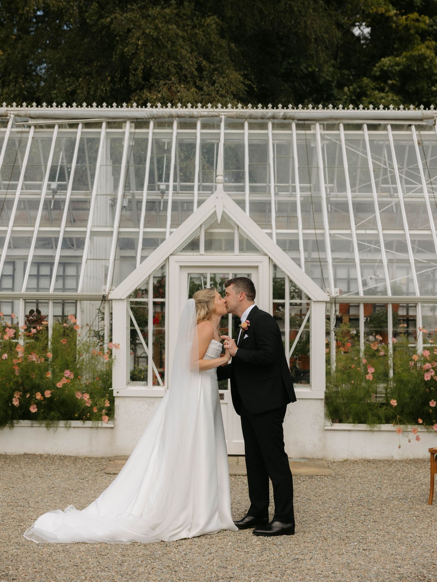 Elegant wedding portraits in front of a classic white greenhouse structure.