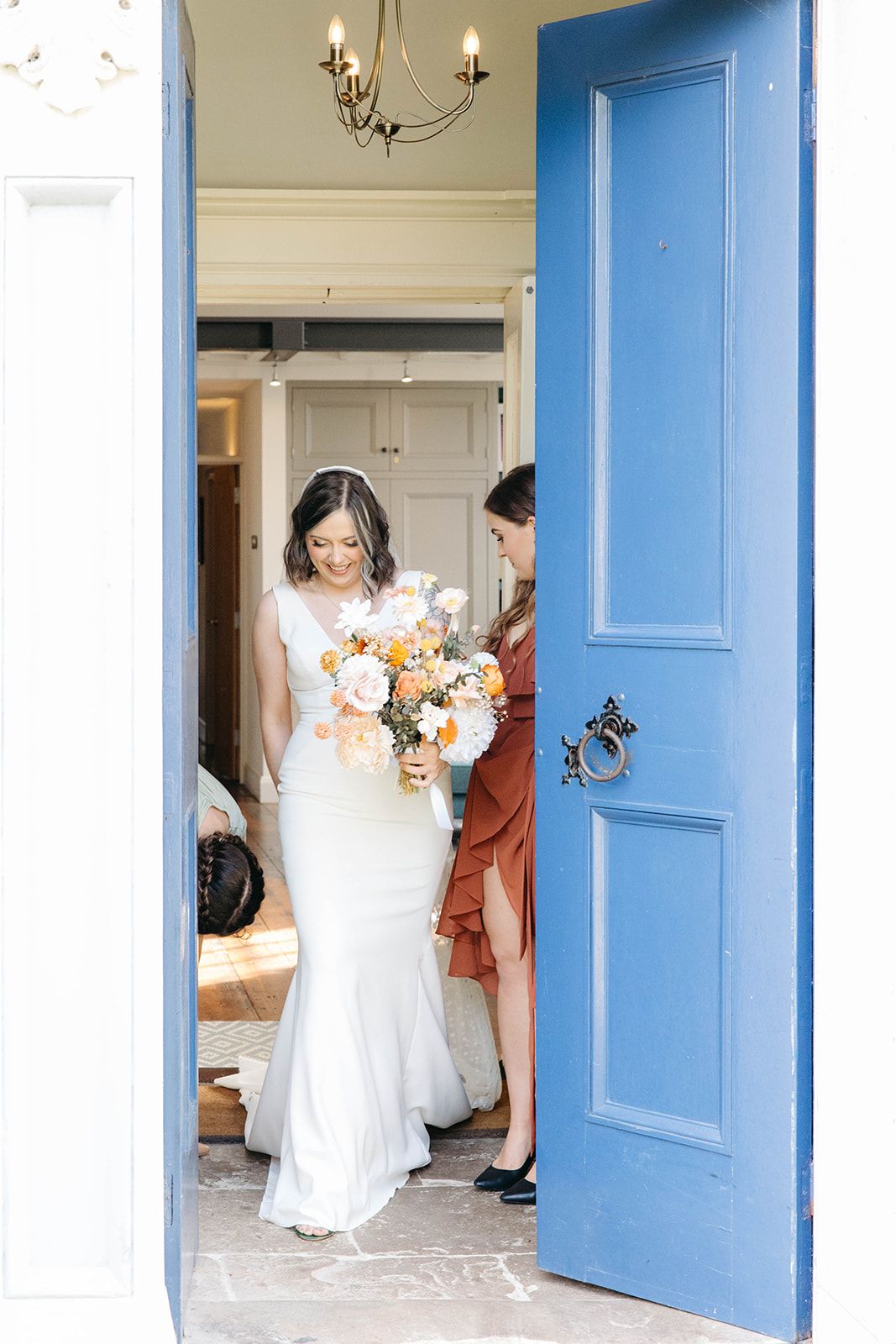 A white wedding dress is framed by a bright blue door as someone prepares for a special occasion.