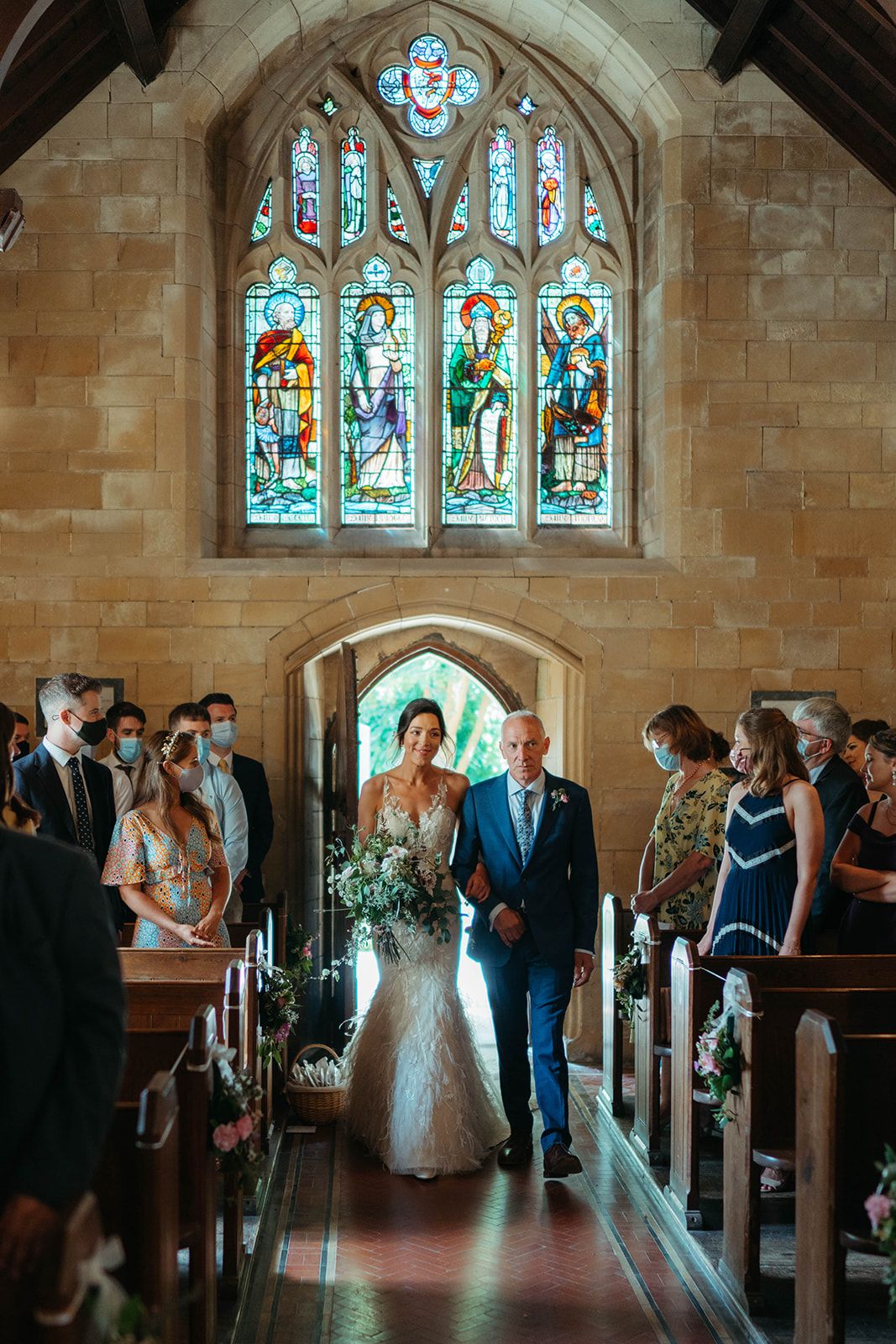 Wedding ceremony in a historic church with beautiful stained glass windows and wooden pews.