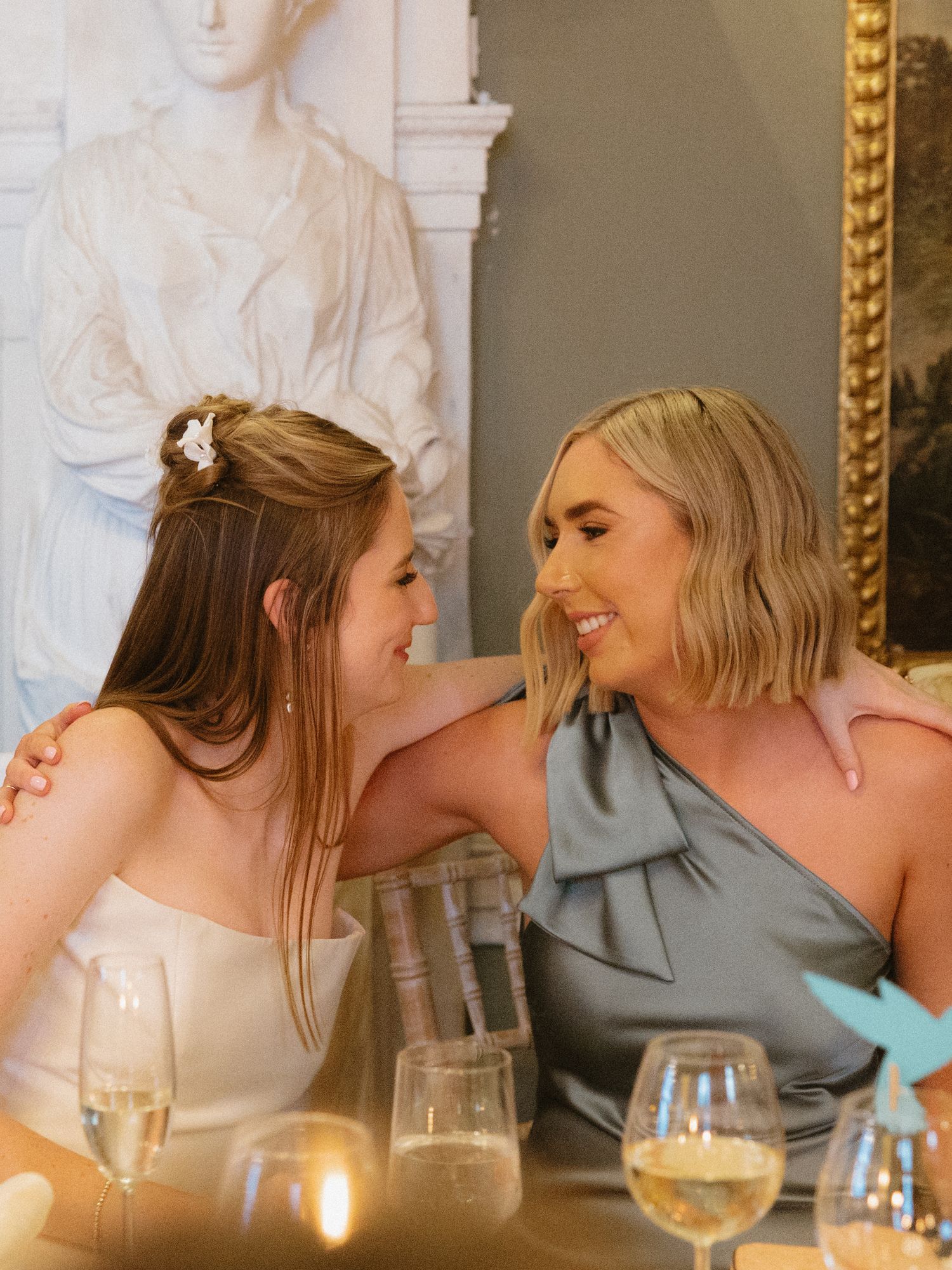 Two guests share a joyful moment at an elegant wedding reception dinner.