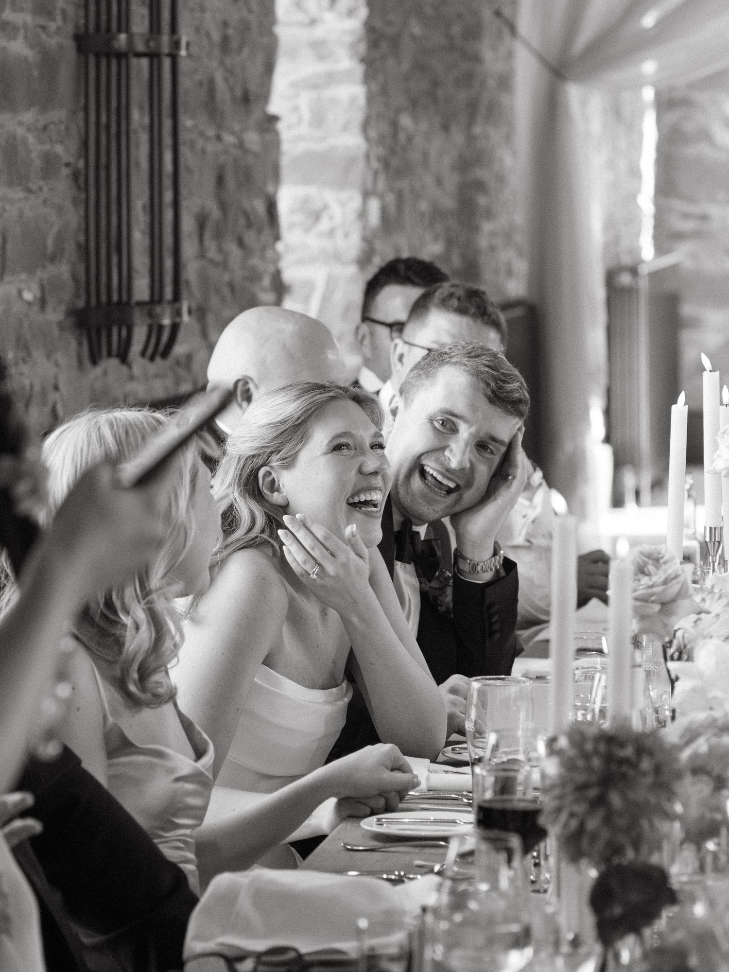 Black and white sequence showing candid laughter during a wedding reception dinner.