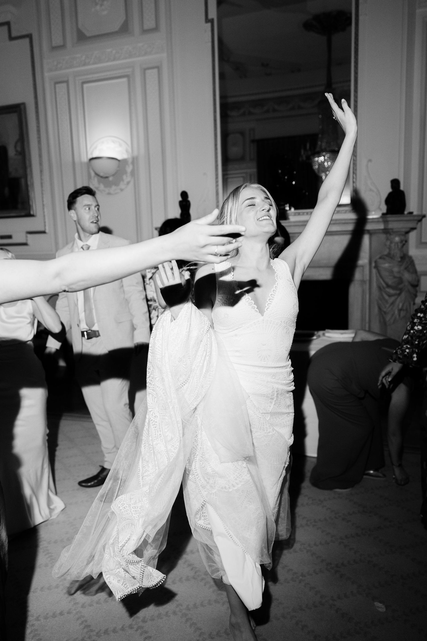 Black and white photograph showing performers in flowing white dresses dancing with expressive arm movements.