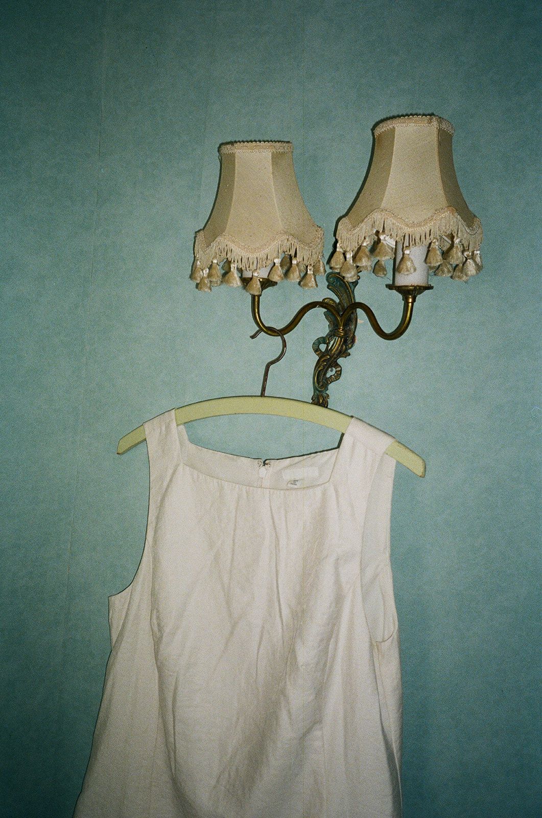Vintage white lace lampshade with fringe details against a teal wall creates a romantic, shabby chic atmosphere.