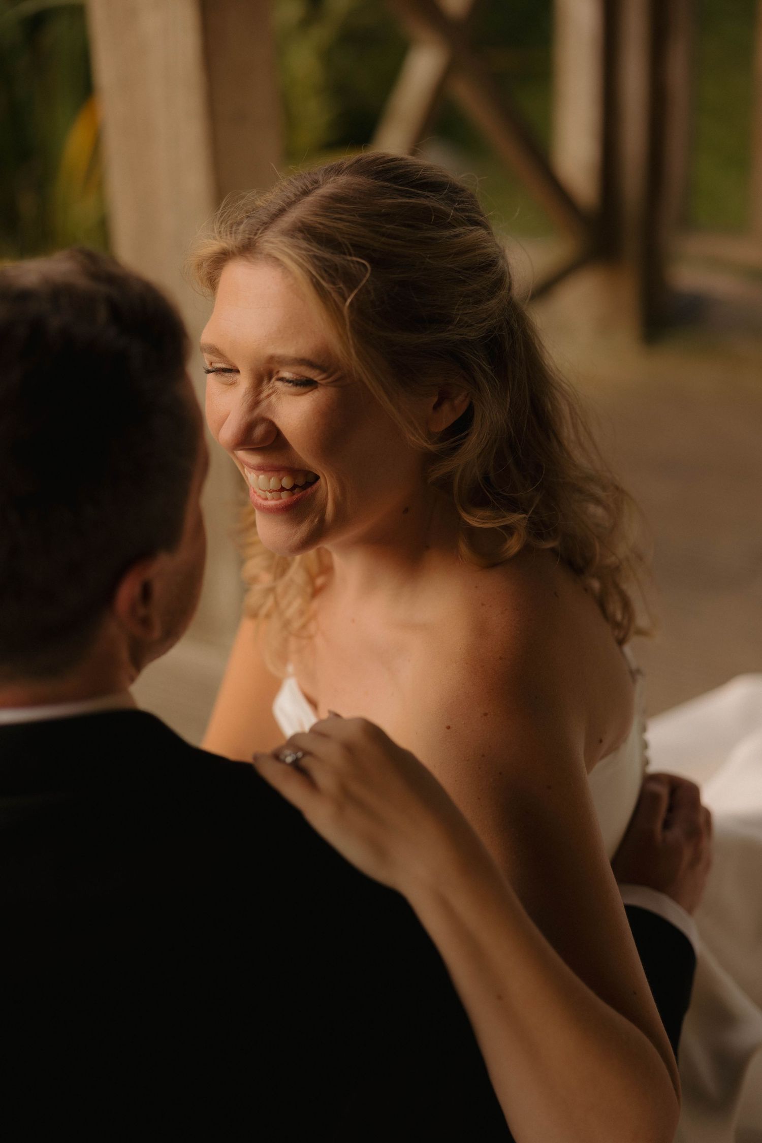 Candid moment of bride laughing during wedding reception.