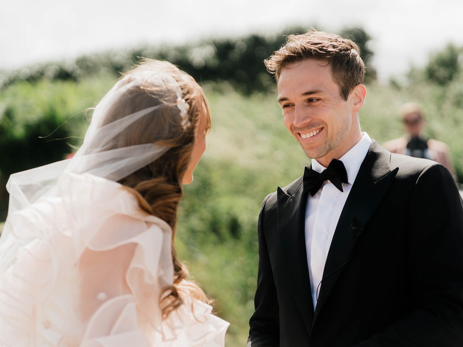 A joyful wedding ceremony captured during the ring exchange against a natural outdoor backdrop.