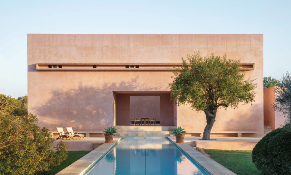 Modern pink stucco house with sleek swimming pool and olive tree in minimalist desert landscape design.