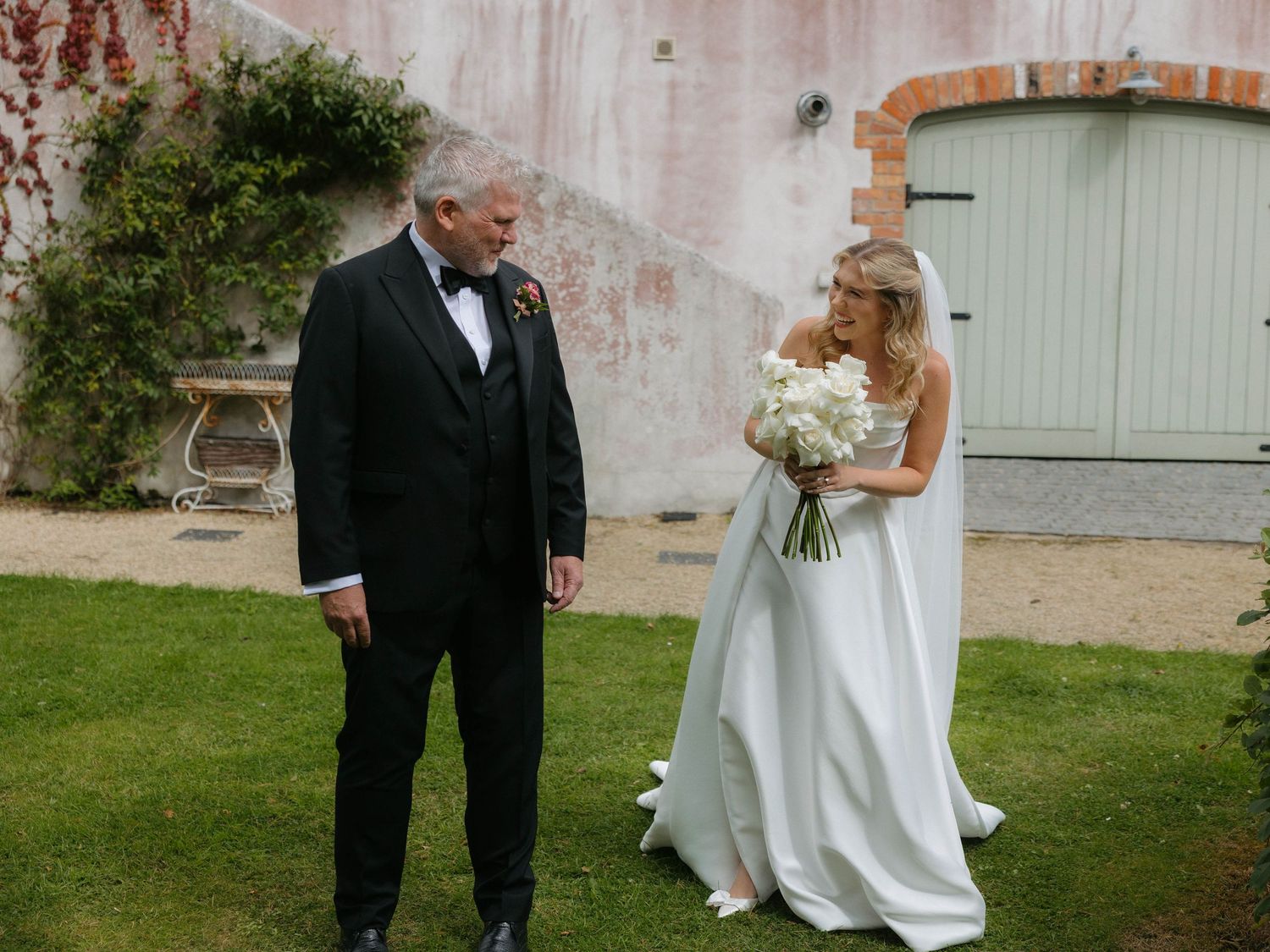 Elegant wedding portraits against a rustic wall backdrop with lush greenery.