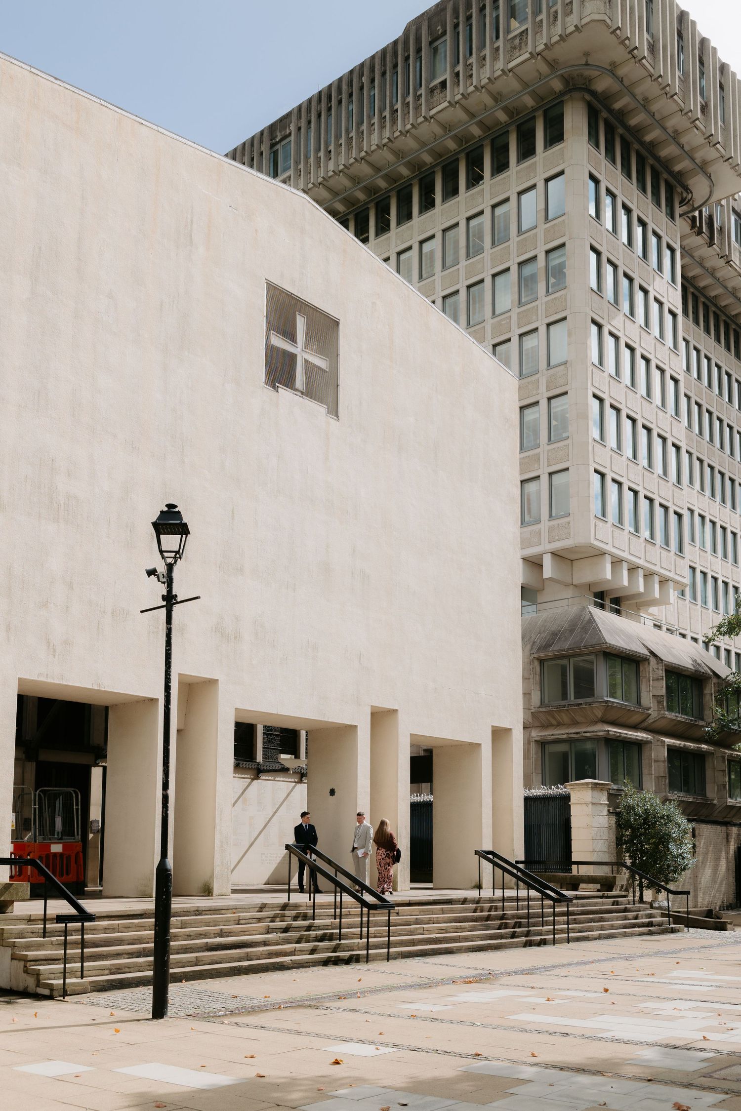 Modern concrete building facade with steps and entryways at different levels shows brutalist architectural style.