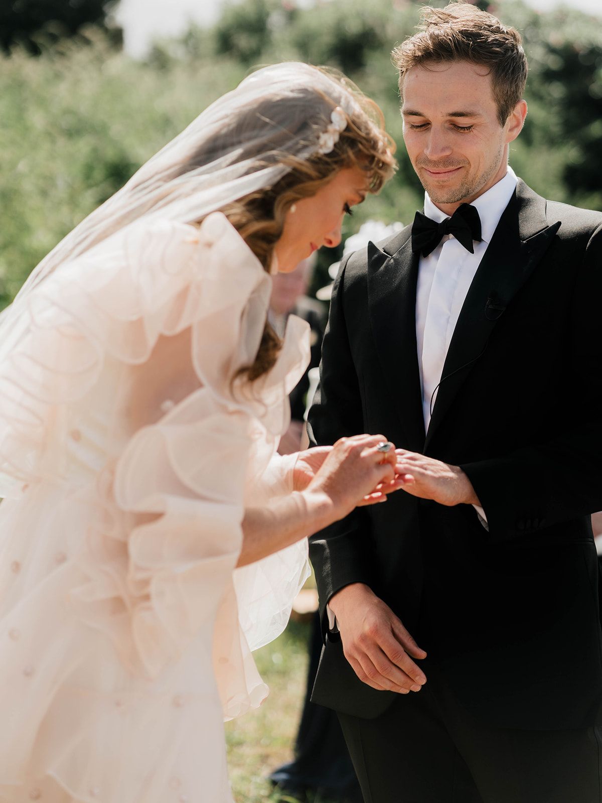 An intimate moment during a wedding ceremony as rings are exchanged outdoors.