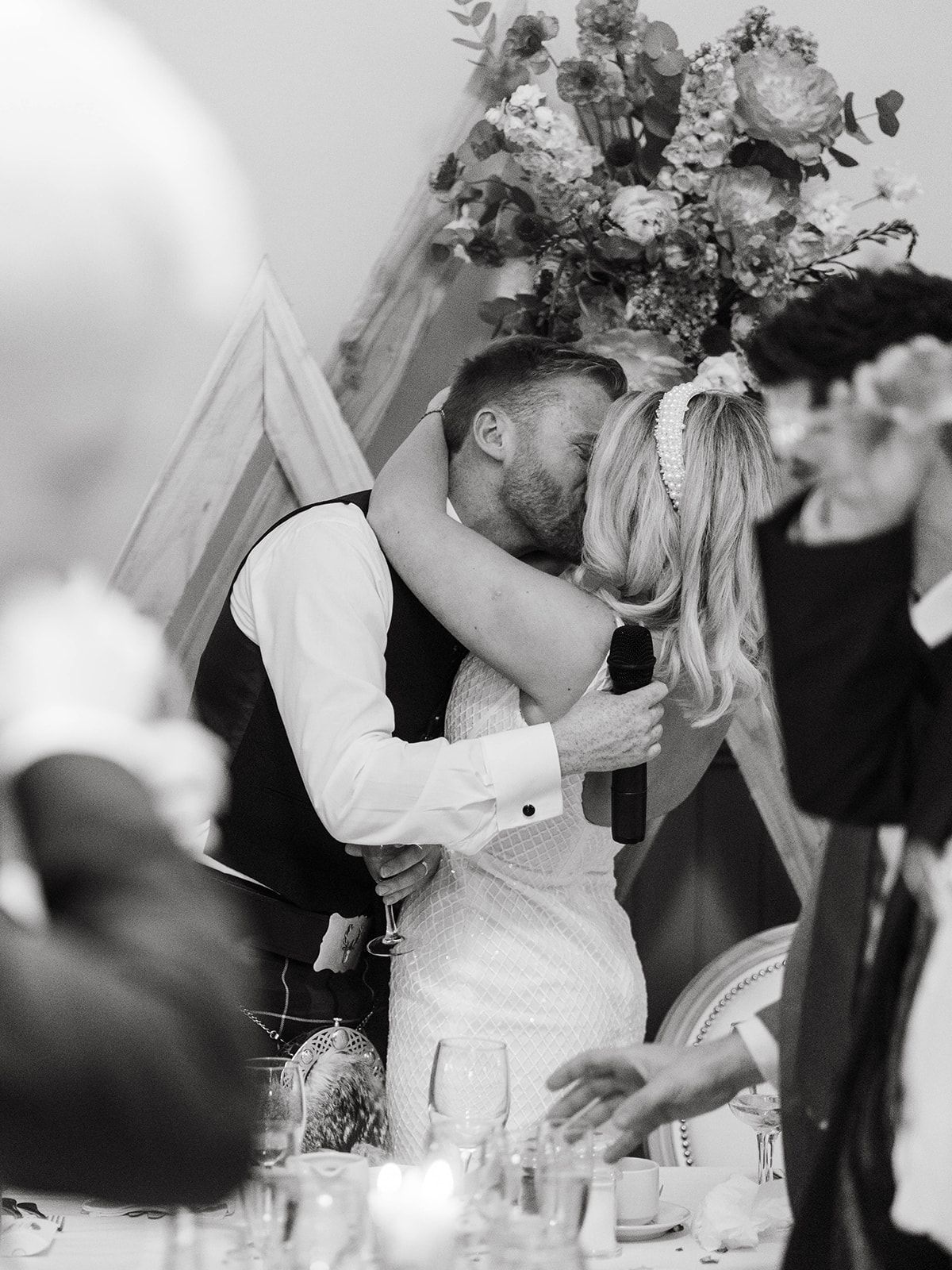 A romantic black and white wedding reception moment captured under floral decorations and candlelight.