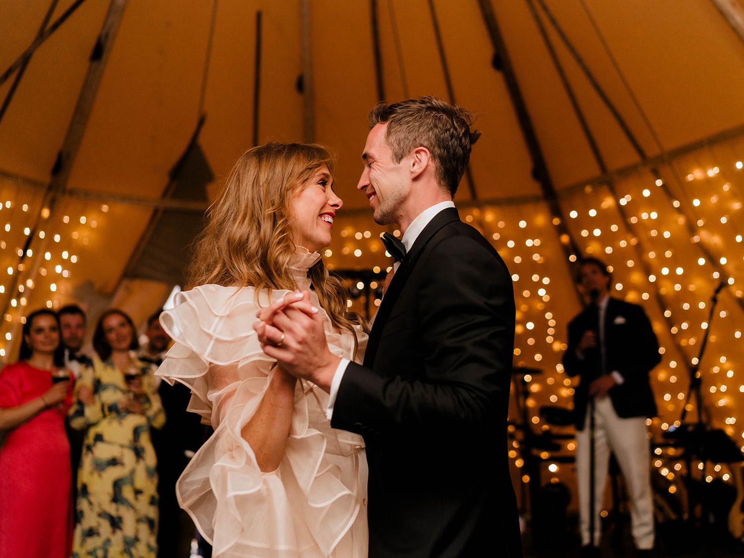 Newlyweds share their first dance under twinkling lights in a romantic tent setting.