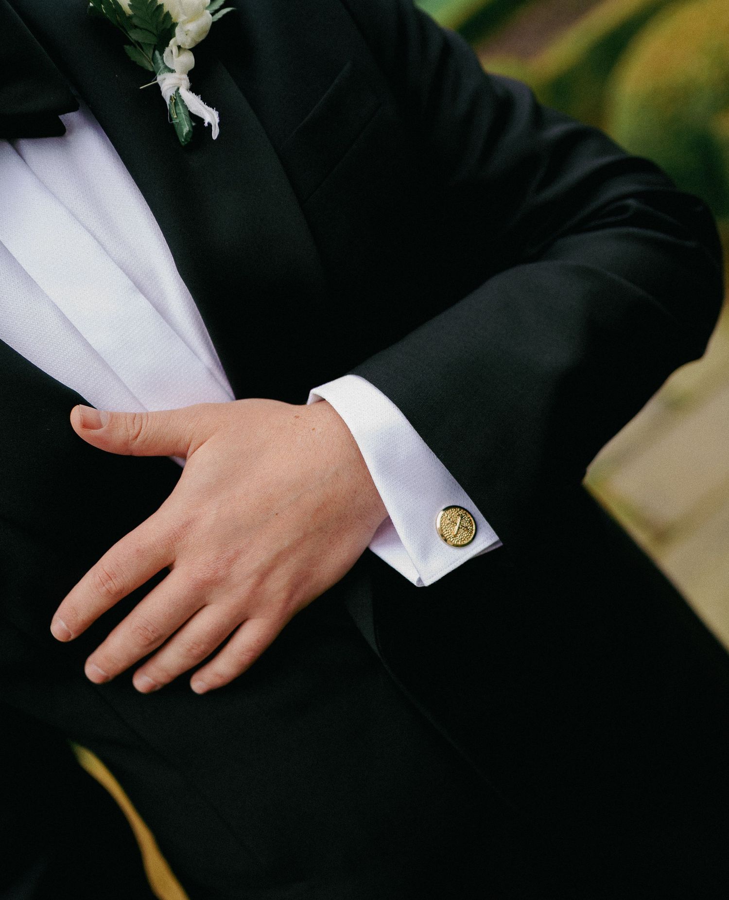 Close-up view of a black suit jacket sleeve with white dress shirt cuff and gold cufflink.