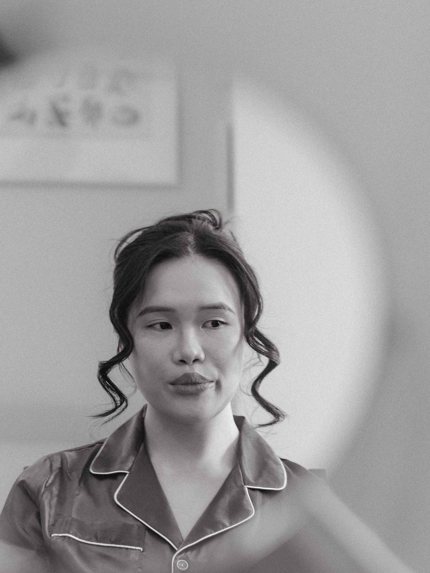 A black and white portrait showing someone in a collared pajama top against a light background with a circular element.