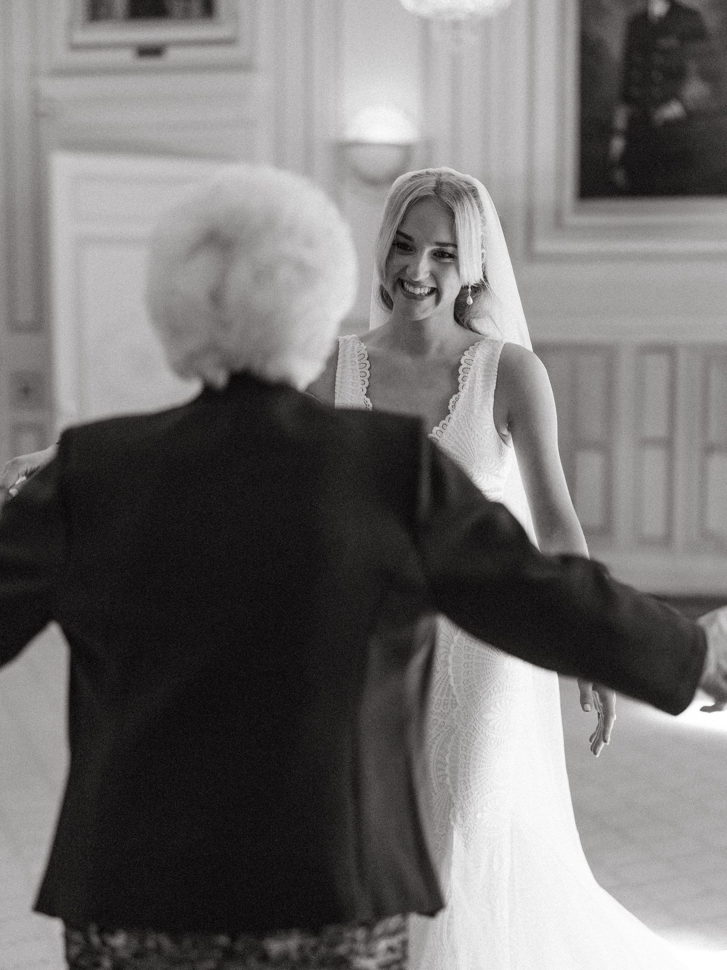 A joyful moment in black and white as a bride in a wedding dress shares a special dance with an elderly guest.