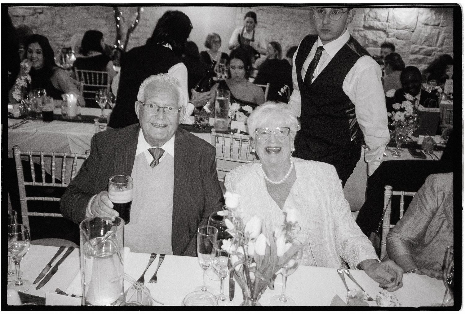 Black and white photograph of guests seated at formal dining tables during a celebratory event.
