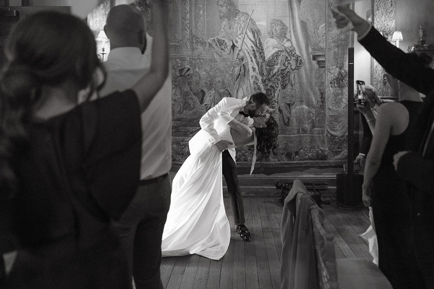 A black and white photograph captures a dramatic dance scene with performers in flowing costumes on a decorated stage.