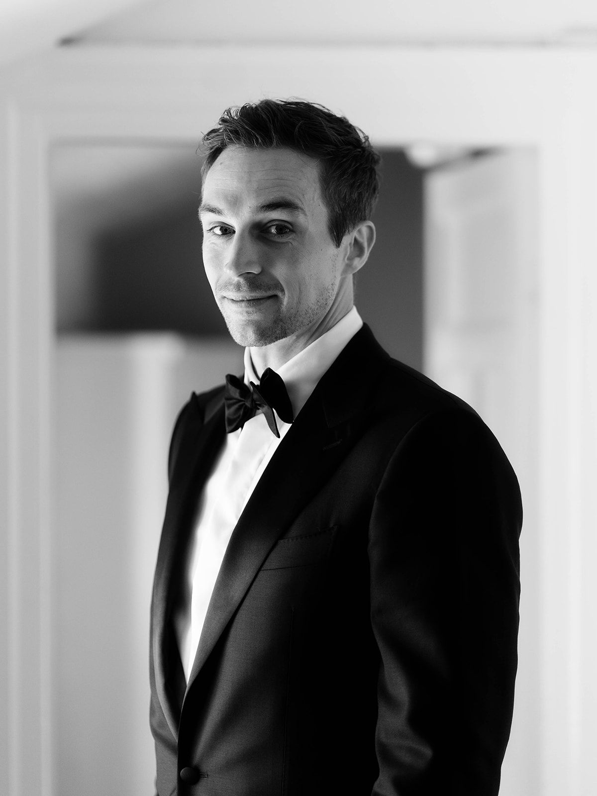 A black and white portrait of a man in a tuxedo and bowtie.