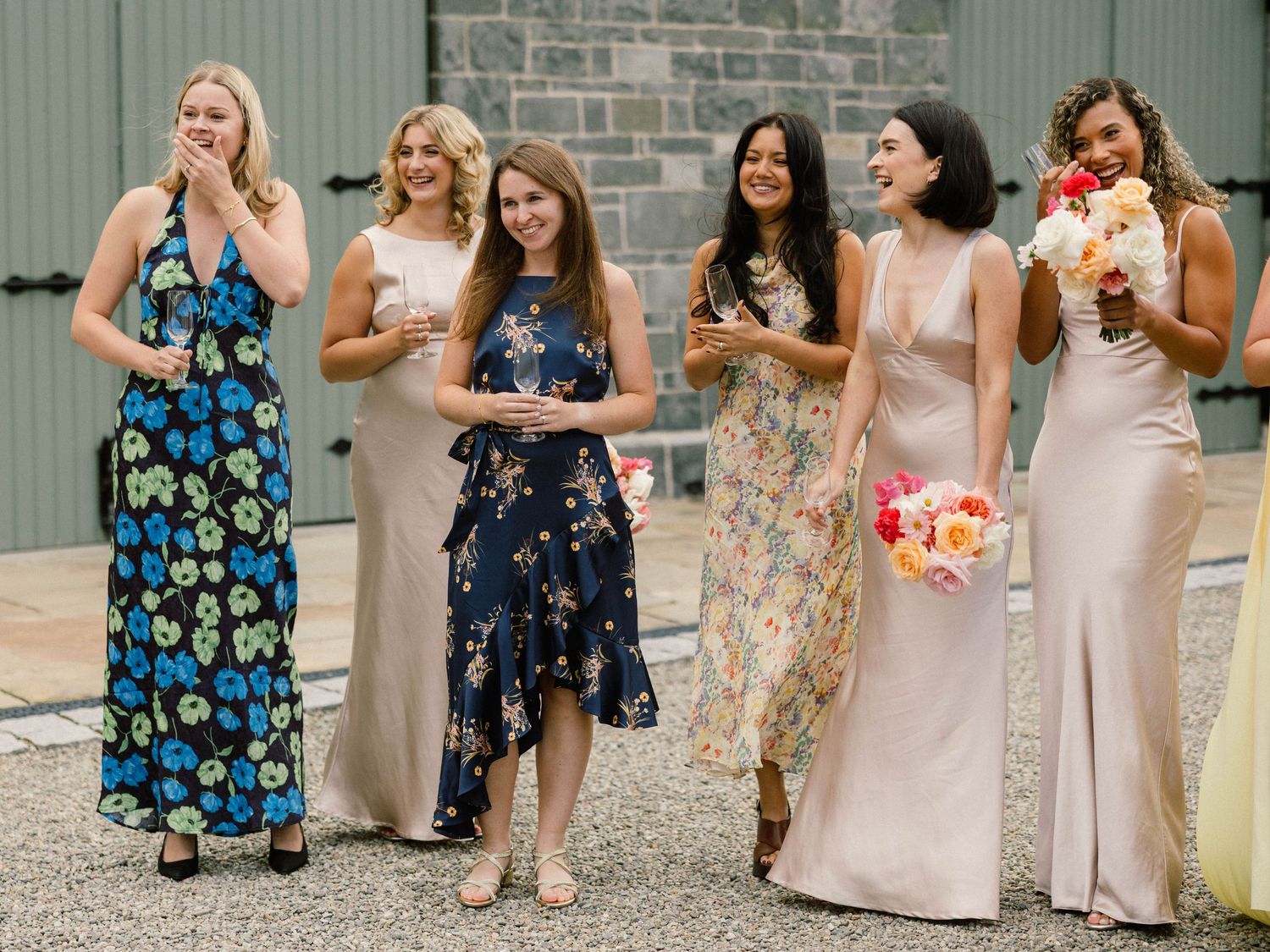 Wedding party in colorful floral dresses gathered for celebratory photos.