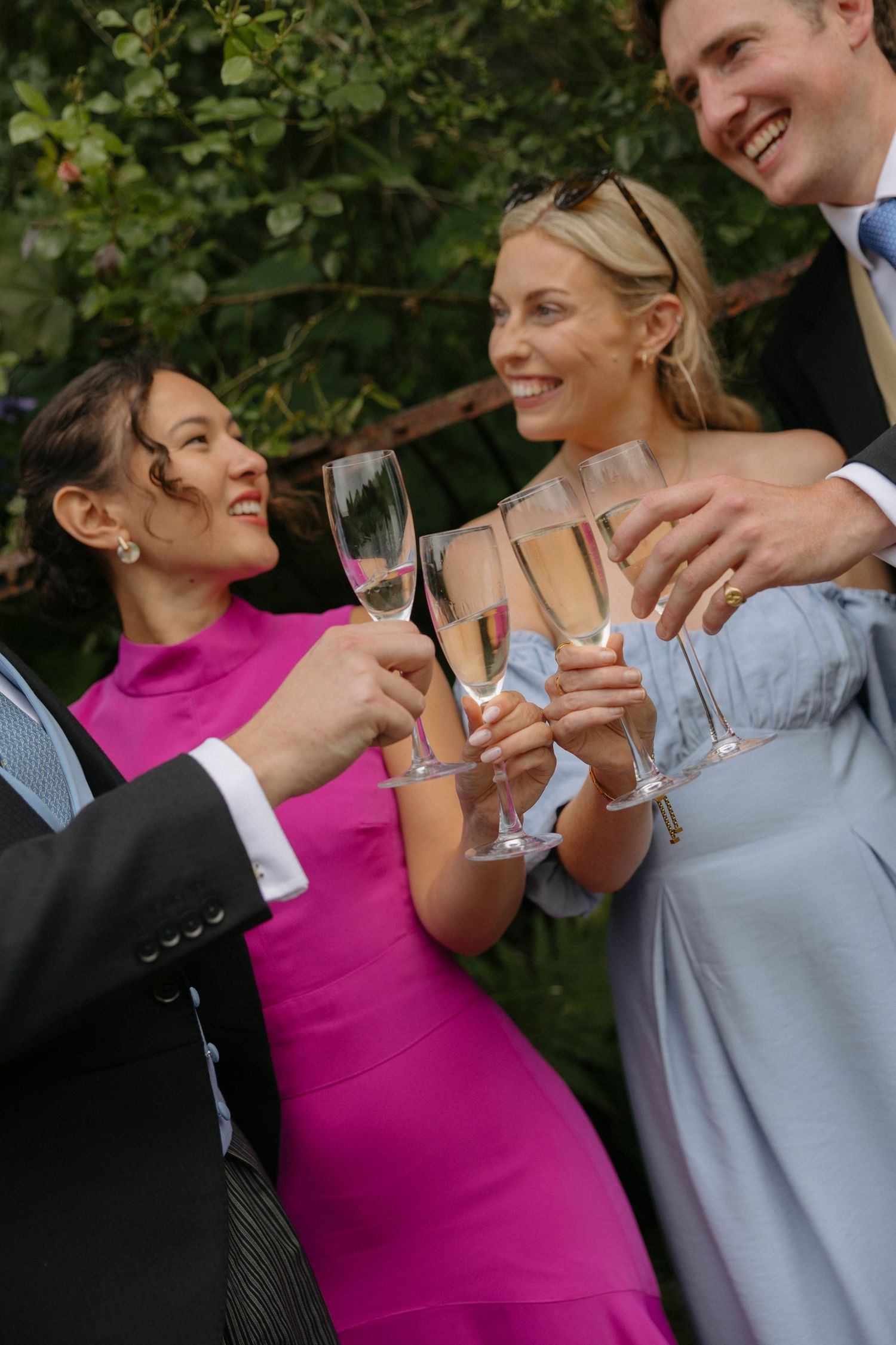 Wedding party members in formal attire share champagne toasts during an outdoor celebration.